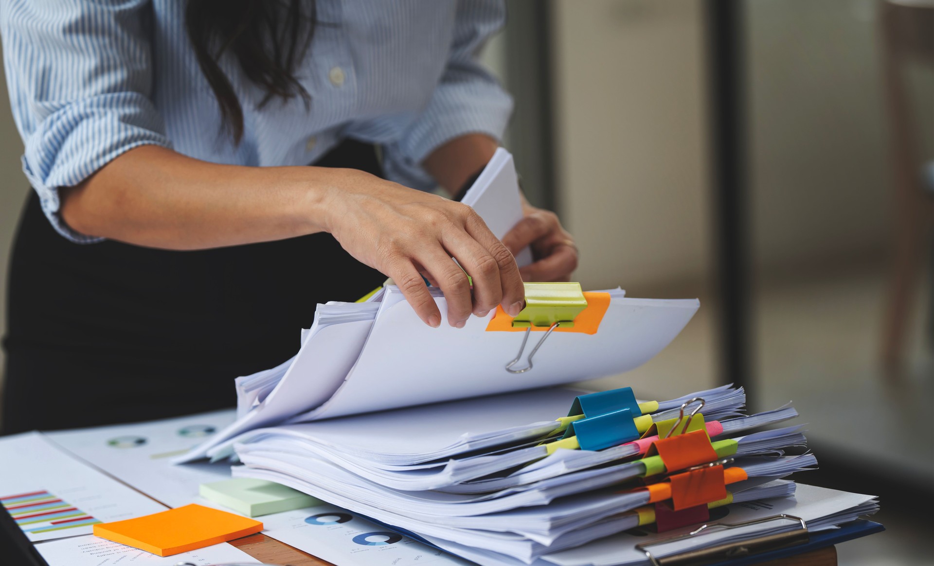 Businesswoman hands working in Stacks of paper files for searching and checking unfinished document achieves on folders papers